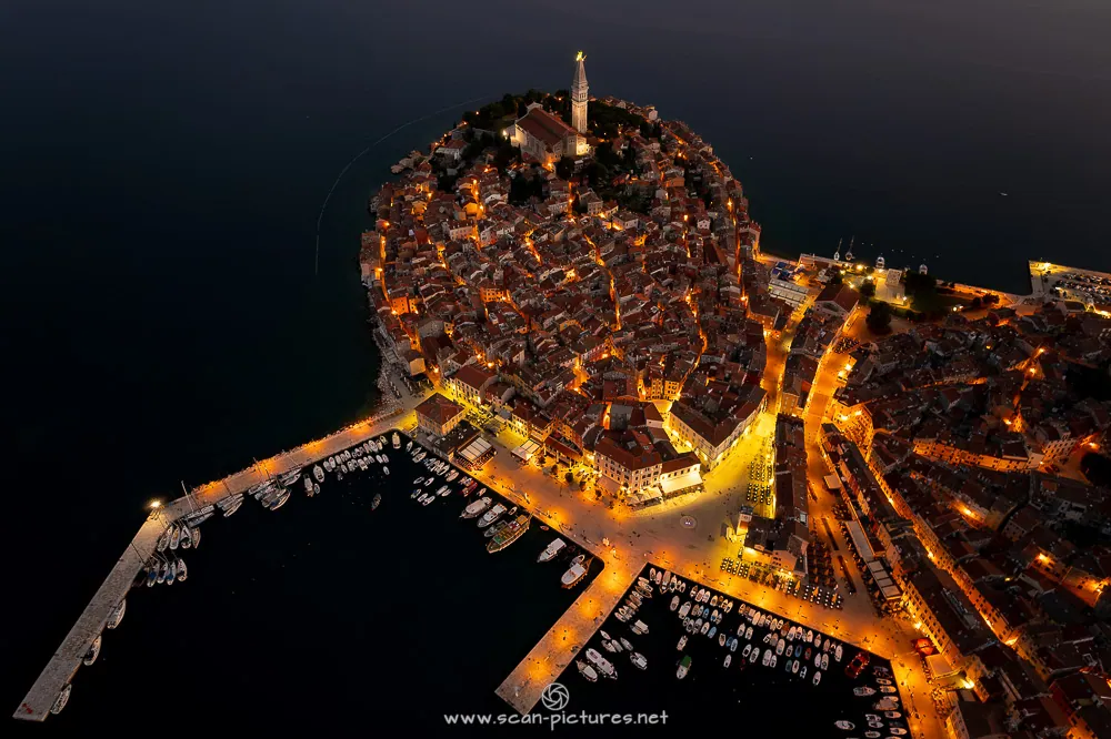 Beleuchtete Altstadt auf einer Halbinsel bei Nacht aus der Luft