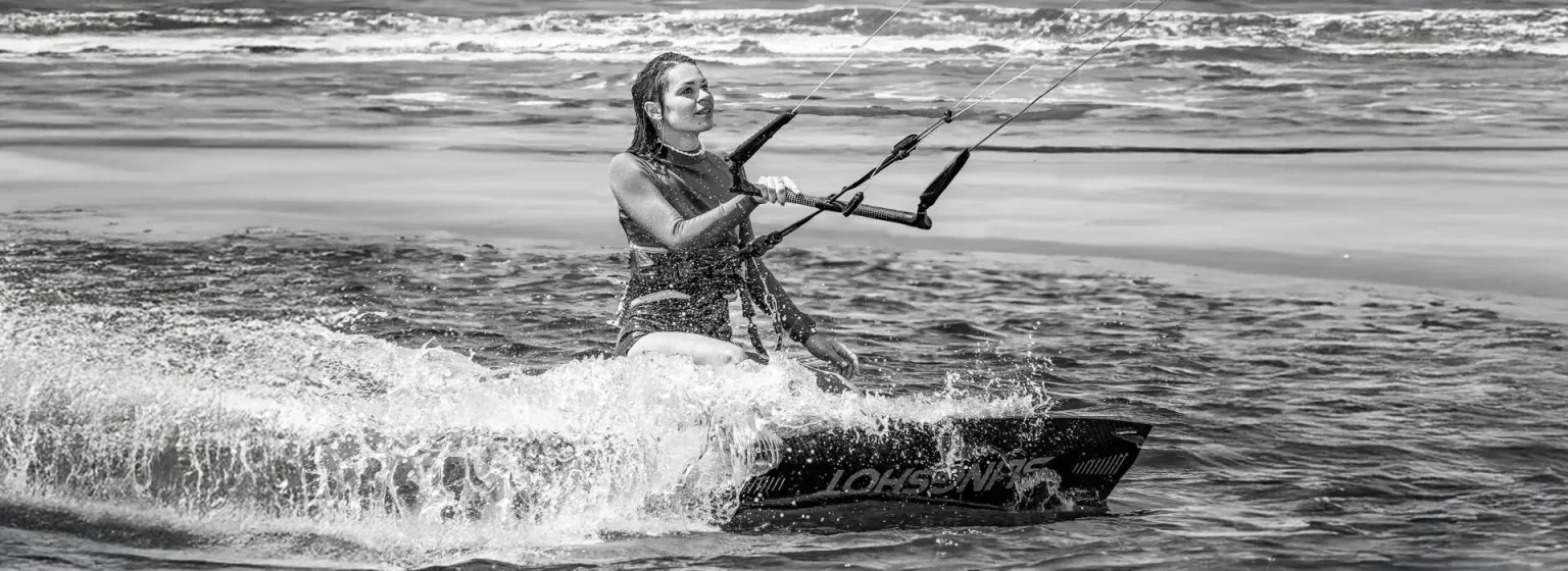 Kitesurferin gleitet durch die Brandung, schwarz-weiß